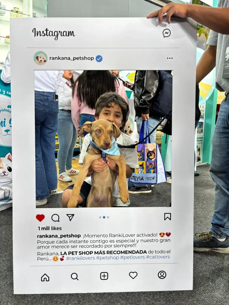 Niño abrazando a un cachorro marrón con bandana de Rankana Pet Shop en el set de fotos de una feria animal.