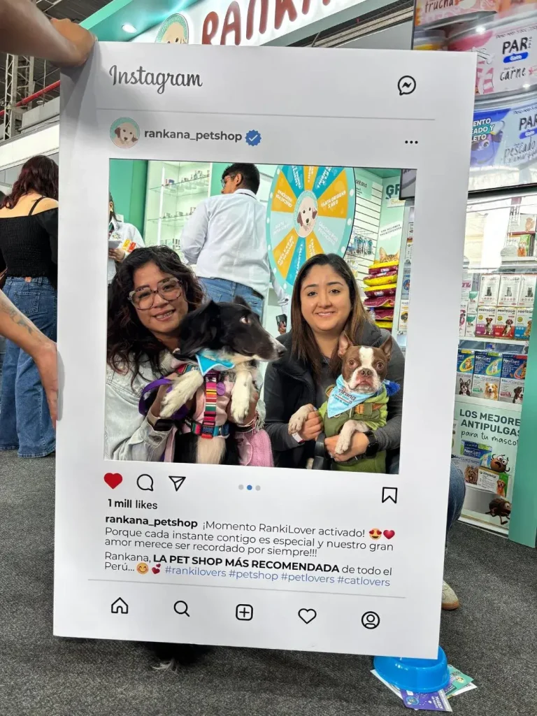 Dos clientas sosteniendo a un Border Collie y un Boston Terrier con accesorios de Rankana en una feria.
